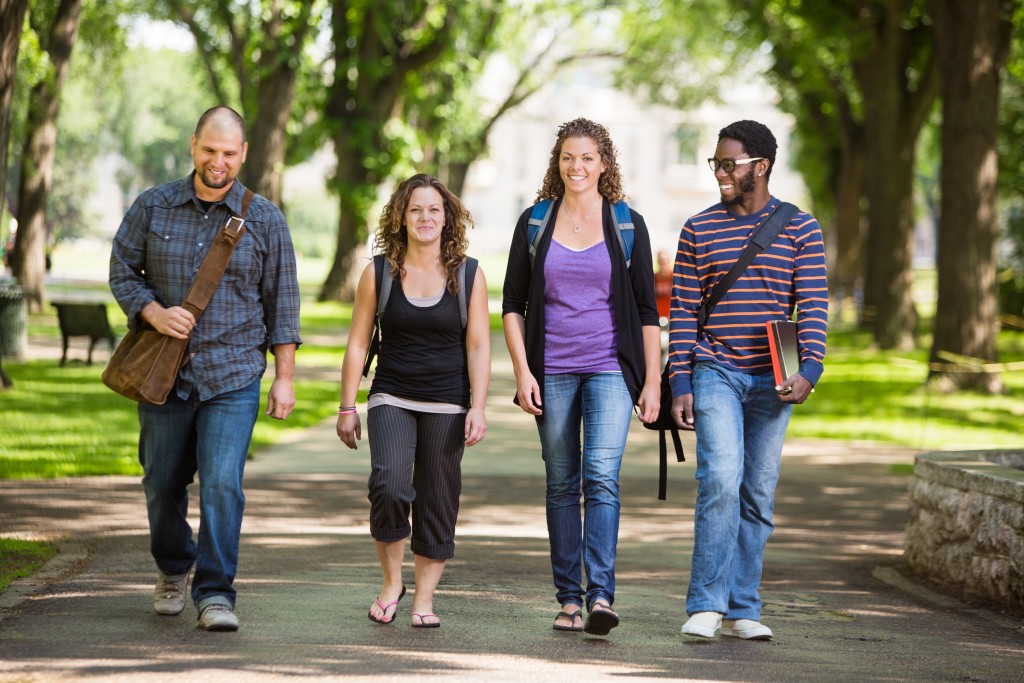 Full length of multiethnic university students walking on campus road